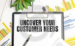 stickers, plant, pen and a white notebook with the text uncover your customer needs