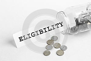 Sticking out of a jar of coins a piece of paper with a text Eligibility on a white background