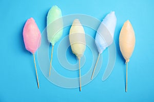 Sticks with different colorful yummy cotton candy on blue background