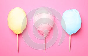 Sticks with different colorful yummy cotton candy on pink background