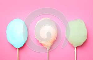 Sticks with different colorful yummy cotton candy on pink background