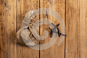 Sticks of dried meat and a paper bag against a wooden background. Pieces of dried beef or jerky. Brown paper bag tied with be.