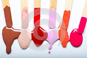 Sticks with nail polish samples. Spilled nail polish. White background.