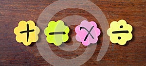 Sticky colorful notes in flower shape, , with math symbols on wooden background.