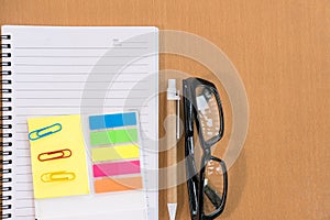 sticky note, ballpoint pen, empty notebook, eyeglasses on office