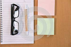 sticky note, ballpoint pen, empty notebook, eyeglasses on office