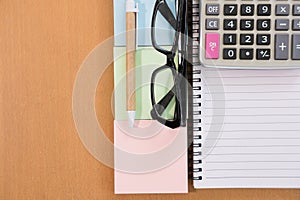 Sticky note, calculator, ballpoint pen, empty notebook, eyeglasses on office desk. business, accountant concept. Top view with cop