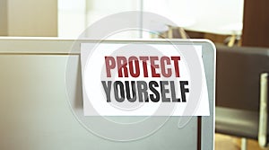 Sticky note on the computer. Text PROTECT YOURSELF