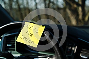 Sticky note with \'Need for Speed\' on car steering wheel photo