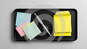 Sticky note pad is visible. The pen is positioned between the