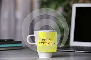 Sticky note with phrase Reset Password on cup indoors