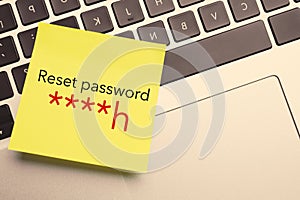 Sticky note with phrase Reset Password on laptop, top view