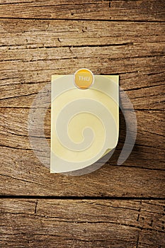 Sticky note with pin over wooden background