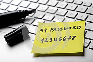 Sticky note with weak easy password on laptop keyboard