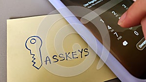 A sticky note with the word Passkeys placed beside a mobile phone