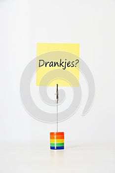 Sticky notepaper with Dutch text meaning Drankjes? (Drinks) clipped to a multicolored card holder
