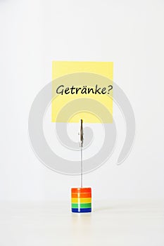 Sticky notepaper with German text GetrÃ¤nke? (drinks) clipped to a multicolored card holder