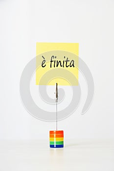 Sticky notepaper with Italian text ÃÂ¨ finita (It's over) clipped to a multicolored card holder