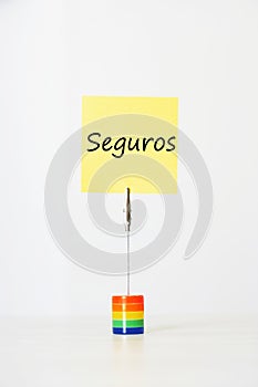 Sticky notepaper with Spanish text seguros (Insurance) clipped to a multicolored card holder photo