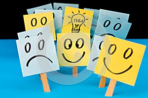 Sticky notes with hand drawn Smiley faces, Sad faces and lightbulb. Positive way of thinking, inspiration and idea concept.