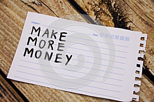 sticky with the phrase make more money written on it. room for text. on the wooden background