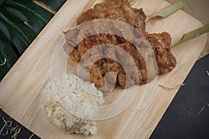 Sticky rice with grilled pork on wooden cutting board. Moo ping is grilled pork in traditional photo