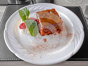 Sticky Toffee Pudding with Raspberries and Mint Leaves on White Plate