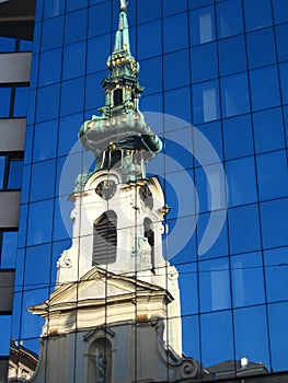 Stiftskirche in Vienna reflecting in opposite glass facade, Austria
