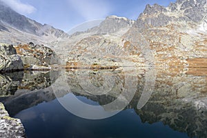 Still alpine lake reflecting rocky mountains with autumn colors surrounding it, Slovakia, Europe