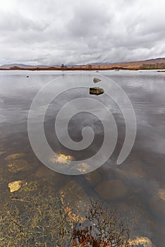The still clear water of Loch Ba in the central part of Rannoch Moor on a wet rainy day in April.
