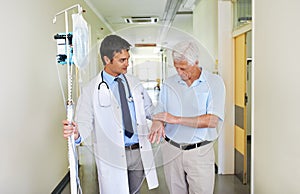 Still feeling alright. a handsome young doctor walking with his senior patient down the hall.