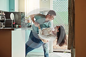 He still knocks me off my feet. Shot of a loving young couple dancing in the kitchen.