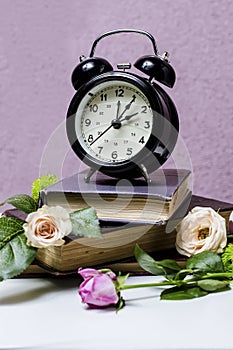 Still life with alarm clock, books and flowers