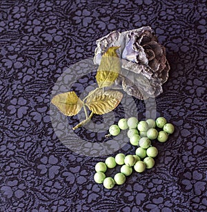 Still life of artificial rose with malachite beads on textile background