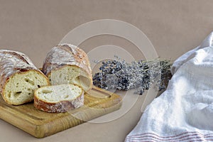 Still-life of baked bread, bouquet of dried lavender, and dish towel on craft paper in rustic style.