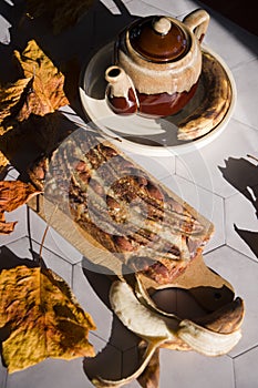 Still life Banana pie with a ceramic teapot in the rays of the autumn sun