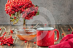 Still life berries of a viburnum in a glass and mug of hot tea a