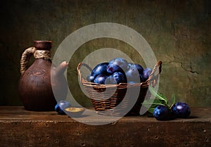 Still life with black plums in a basket