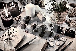 Still life with black and white candles, runes, cones and open diary book on table.