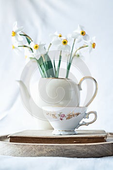 Still life with a blooming bouquet of white daffodils and coffee cup