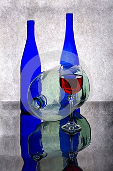 Still life with blue bottles, a glass of red wine and a glass bottle