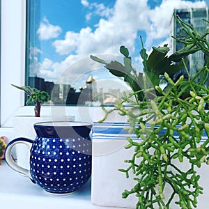 Still life with a blue cup on the window, in which clouds are reflected