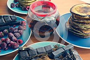 still life on blue plates pancakes with peas, grated chocolate, chocolate bars, brewed tea