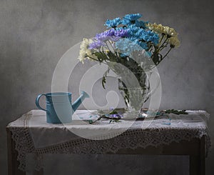 Still life with blue watering can and a bouquet of chrysanthemums