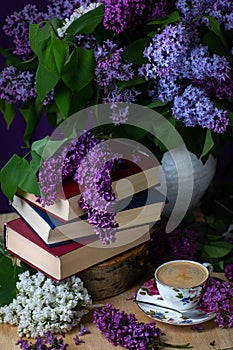 Still life books, coffee and lilacs in the dark key.Spring background