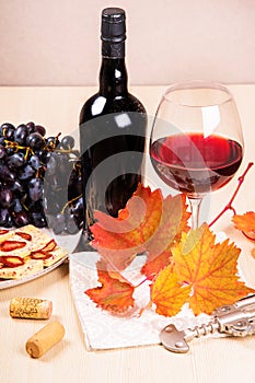 Still life with a bottle and a glass of red wine, grapes and chocolate with strawberries