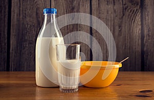 Still life of bottle of milk, glass of milk and yellow plastic bowl