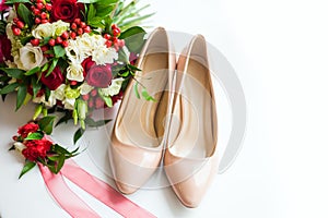 Still life from a bouquet of flowers and the bride`s shoes on a white background