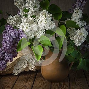 Still-life with a bouquet of lilacs and a straw hat