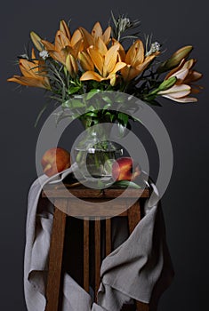 Still life with a bouquet of summer flowers and peaches on a dark gray background